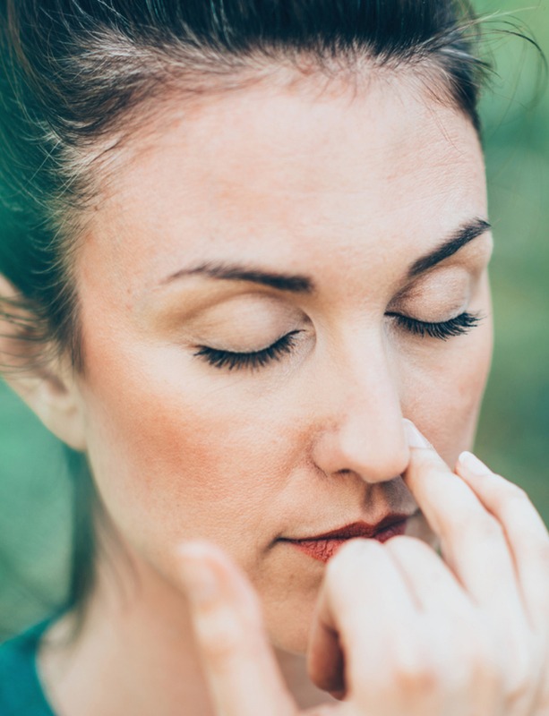 A woman doing nostril breathing and closing one nostril, a meditation found in SleepSpace.